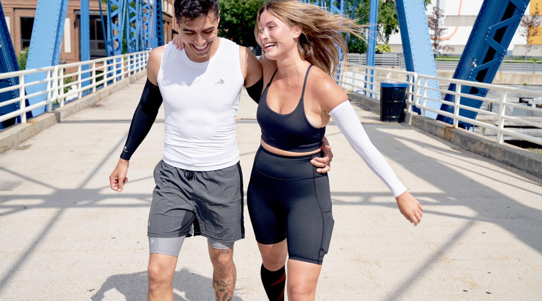 Guy and girl walking wearing compression shorts, tops and arm sleeves.